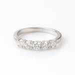 Sterling silver engagement-style ring with five round cubic zirconia stones, photographed on a white reflective background.